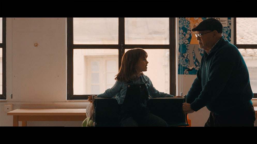 Un hombre mayo empujando un carro con una niña montada