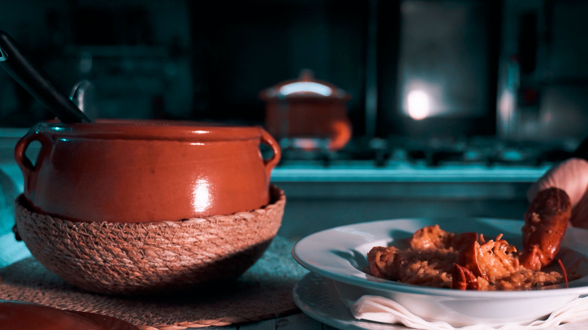 Caldero de barro y plato al lado con guisado de bogavante